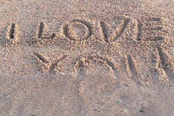 Fototapeta na wymiar I love you written on the sand being washed away by water 