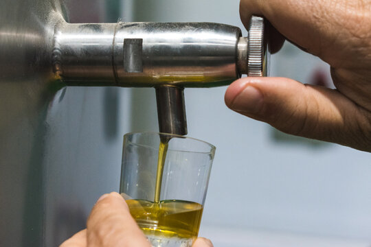 Closeup of a man's hand opening an extra virgin olive oil tap