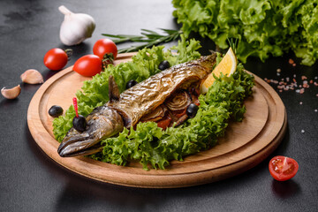 Baked mackerel with vegetables on a wooden board with lemon