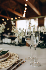 Champagne glasses. Candles and flowers. Banquet table decoration.