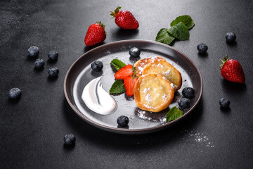 Tasty baked pancakes with berries and mint with powdered sugar and topping on a gray plate