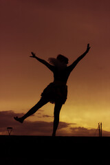 Silhouette of young ballerina dancing and having fun outdoors