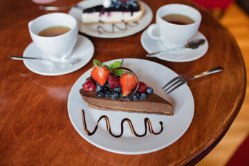 Chocolate pie with berries on table surrounded by cups of tea in a cafe