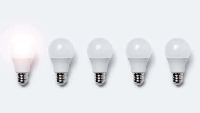 Stop motion animation photography; close-up of many light bulbs glowing on white background. Business idea concept.