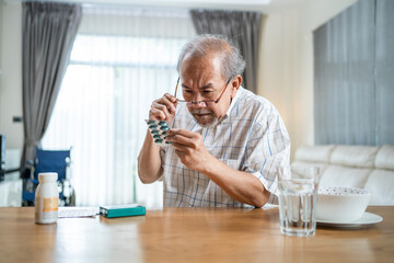 Asian old man read drug label, check instructions before or after meal	
