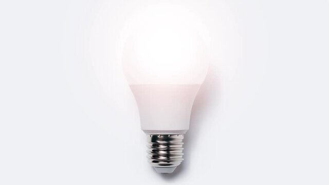 Stop motion animation photography concept. Close-up of light bulb glowing on white background.