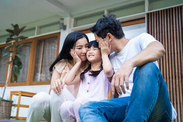 Asain happy family, Parent kiss little girl's cheek in garden at house - obrazy, fototapety, plakaty