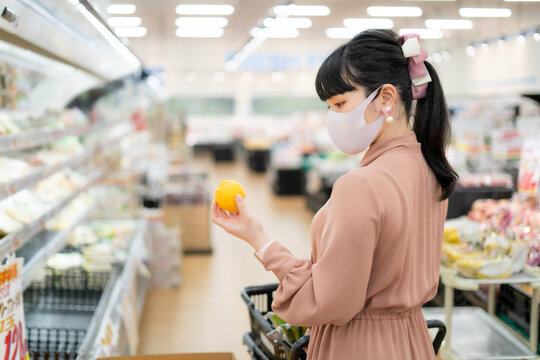 スーパーマーケットでレモンを持つ女性