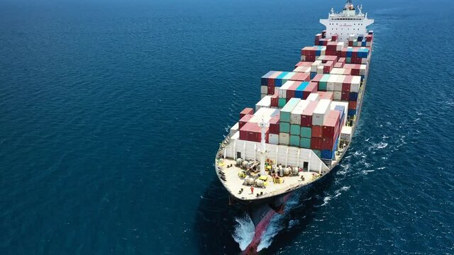 Aerial drone video of bow from huge container tanker ship carrying truck size colourful containers in deep blue Mediterranean sea