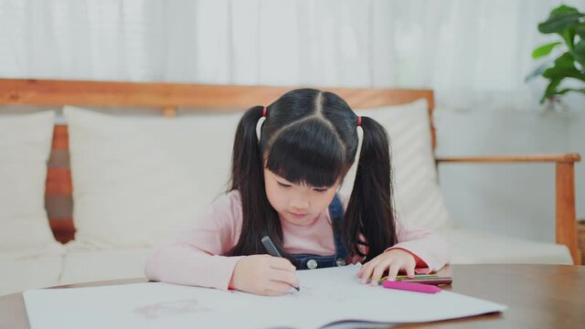 Asian young kid draw and color picture on paper in living room at home