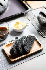 Organic homemade charcoal black bread. set on cafe table with butter and coffee.