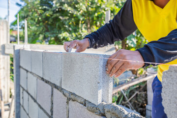 Worker masonry are building walls with cement blocks and mortar.