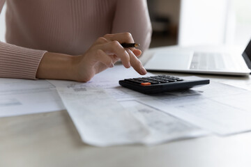 Crop close up of woman sit at desk manage family budget calculate expenses expenditures on machine....