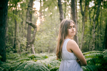 Happy girl in the summer village . Girl in a white dress among the ferns.  Girl and fern. Girl  in a dress and white hat among a green park in the morning