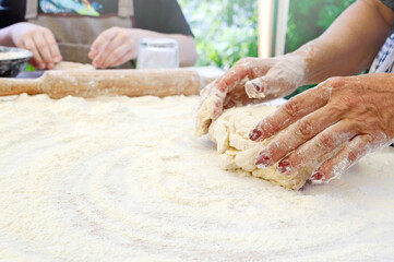 The cook teaches children to making dough. The female hand kneads the dough on a floured table....