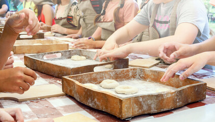 Children make donuts out of dough and place them on wooden trays. Master class in baking.