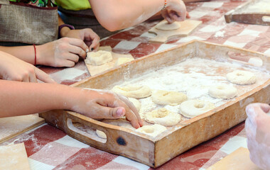 Children make donuts out of dough and place them on wooden trays. Master class in baking.