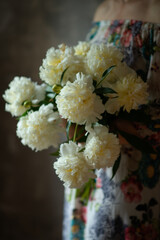 A girl holds a bouquet of white peonies.