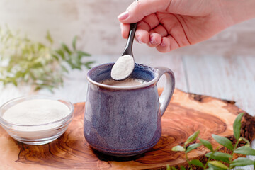 Woman adding collagen powder to her morning coffee. Beauty collagen supplement, additional collagen...