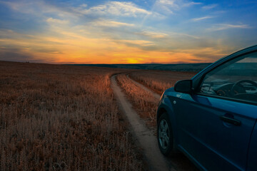 Travelling by car. Country field road at sunset. Countryside landscape.