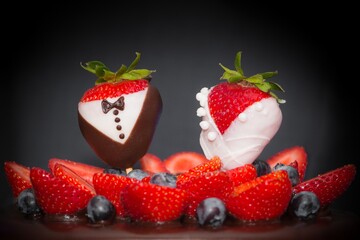 Strawberry bridal couple bride groom at chocolate wedding cake. Confectionery luxury art trend marriage strawberries bridal couple embellishment, blueberries and frosting cream. Food symbol of love