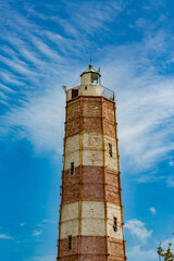 Shabla lighthouse and Black Sea, Bulgaria. Partial view against overcast blue sky. Sunny spring day, travel photograph of this tourist destination on the Northern shores.