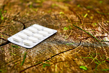 White pills in a blister on a wooden stump