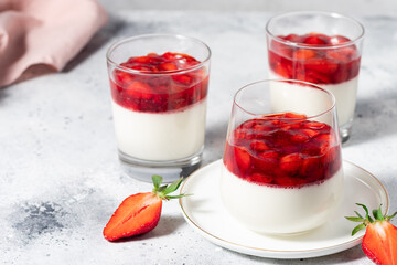 Vegan coconut panna cotta with strawberry sauce in glasses. Healthy vegan food. Gray background