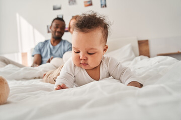 Fototapeta premium Child laying at the bed and relaxing while his parents embracing