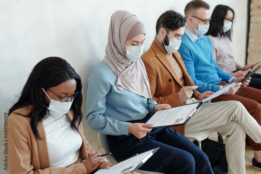 Poster job candidates in masks examining resume before interview