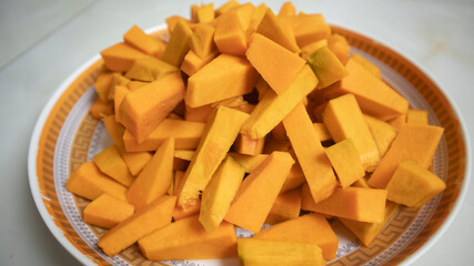 Chopped yellow raw pumpkin prepared on plate before cooking at home.
