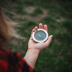 A girl in a red checkered shirt holds a compass in hand and is guided by the area, walk,hiking