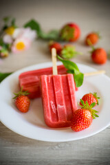 homemade strawberry ice cream on a stick made from fresh strawberries in a plate