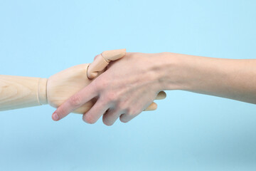 human and wooden hand puppets shake hands on blue background