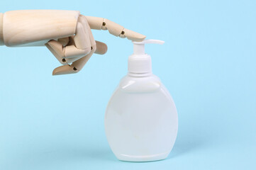 Wooden hand presses on bottle of cream on blue background