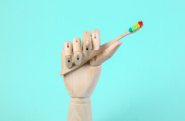 Wooden hand holds toothbrush on blue background