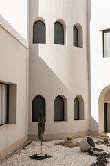 Modern east style building with windows and sunlight shadows on beige walls. Abstract minimal...