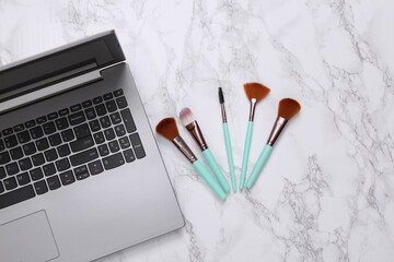Online beauty blog. Notebook with makeup brushes on a marble surface. Top view