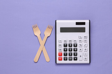 Calculator and wooden forks on purple background