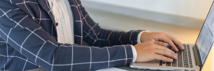 Business partners concept a young businessman using a laptop revising annual sales summary