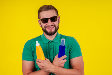 man holding bottle of sun cream in studio yellow background