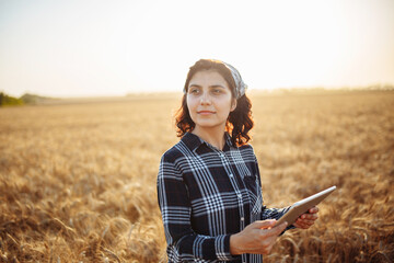 Portrait of a woman farmer in a wheat field with a tablet. A woman agronomist checks the harvest....