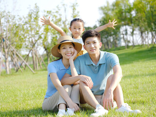 Happy family of three sitting on the grass