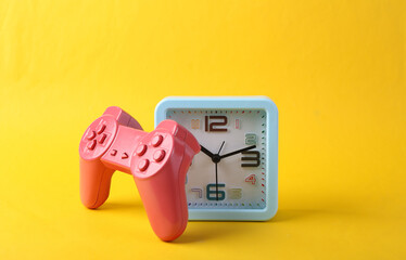 Alarm clock and gamepad on yellow background. Time to play © splitov27