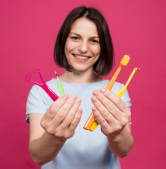 Beautiful young woman uses an oral care kit consisting of a tongue scraper, single tufted and interdental brush