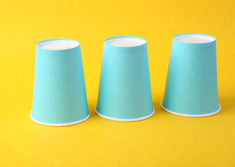 Three inverted cardboard cups on a yellow background. Gambling