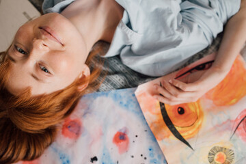 Girl posing around her pictures and smiling while laying at the bed