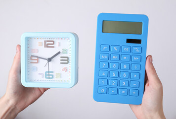 Hands holding alarm clock and calculator on white background.