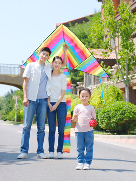 Happy family of three flying kites outdoors