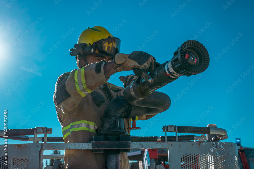 Wall mural firefighter on ladder next to lance to launch pressurized water.